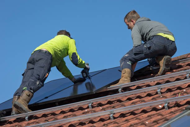 zonnepanelen Wierden, Overijssel, Netherlands, march 24th 2020, low angle close-up of two male workers standing on top of a residential building with orange roof tiles, mounting solar panels on a frame over the rooftiles - this form of renewable energy for house owners is gaining popularity, the total solar panel power production in the Netherlands in 2020 increased by more than 50% compared to 2019